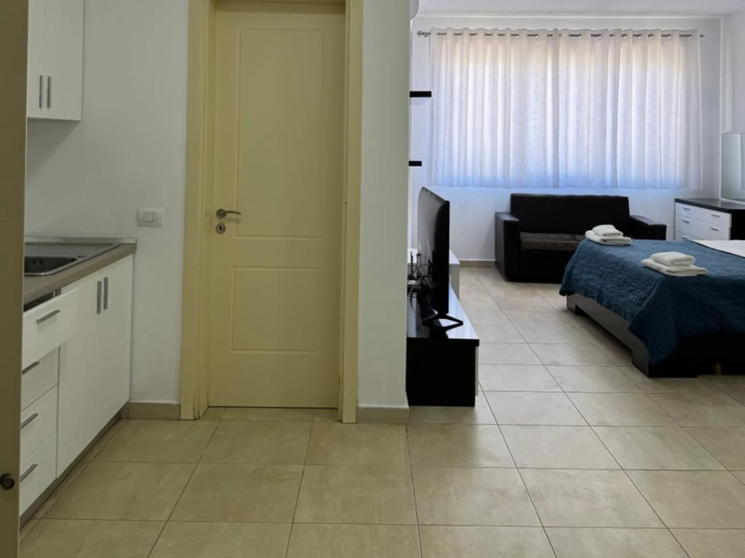 Open-plan studio apartment with kitchen, double bed and sofa at Casa Italia in Tirana
